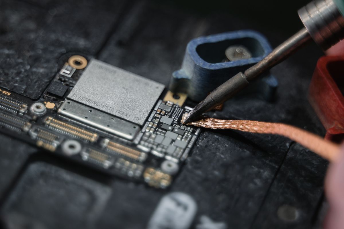 Close-up of manual circuit-board rework using desoldering braid
